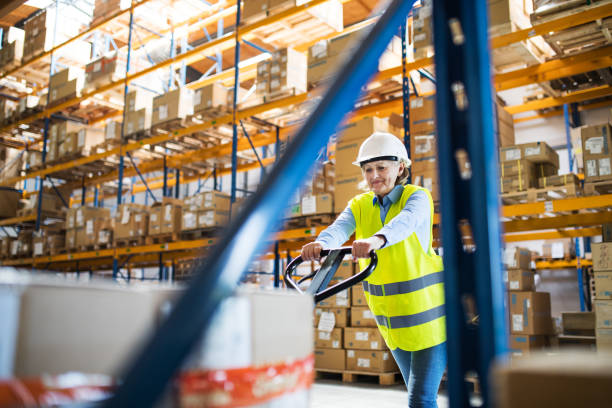 istock A senior woman warehouse worker pulling a pallet truck with boxes. 981706012