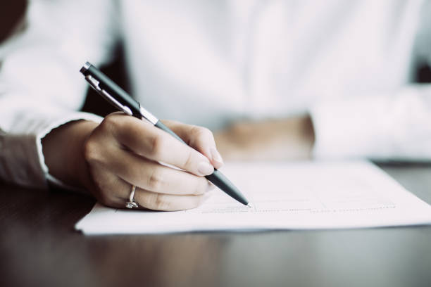 istock Hand of businesswoman writing on document at table 981710770