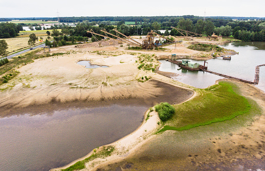 Aerial view of a wet quarry for gravel and sand with large machines for excavation and processing, made with drone