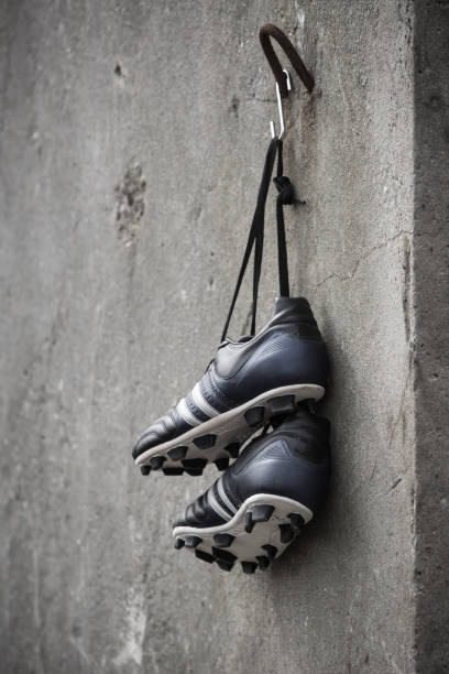 istock Soccer shoes hanging on a rough concrete wall. 981731762