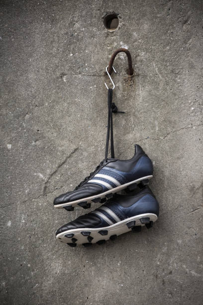 istock Soccer shoes hanging on a rough concrete wall. 981731768