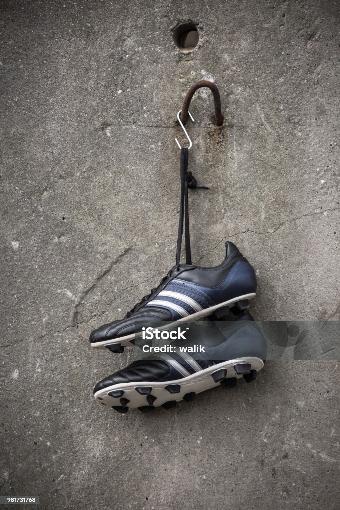 Soccer shoes hanging on a rough concrete wall. Soccer shoes hanging. Hanging Stock Photo