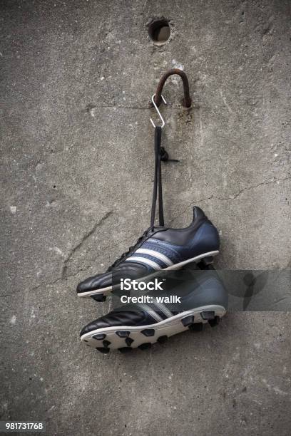 Soccer Shoes Hanging On A Rough Concrete Wall Stock Photo - Download Image Now - Hanging, Soccer Shoe, Soccer