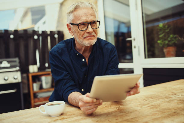 istock Content senior man holding a tablet and drinking coffee outside 981732560