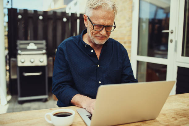 istock Smiling senior man working on a laptop and drinking coffee 981733692