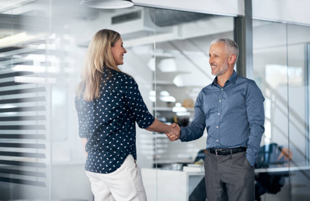 I've heard great things about your company Shot of a businessman and businesswoman shaking hands in a modern office casual handshake stock pictures, royalty-free photos & images