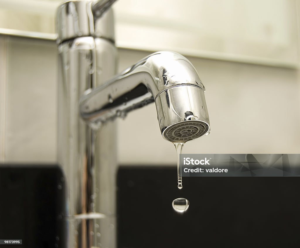 A silver tap with a droplet of water falling out Water tap closeup Cold Temperature Stock Photo