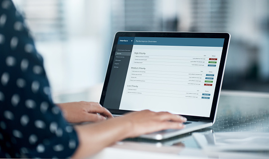 Cropped shot of a businesswoman using a laptop at her desk in a modern office