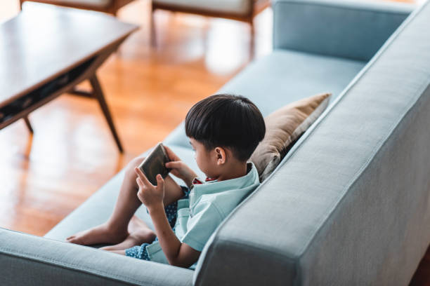 Chinese boy using smart phone in the living room stock photo