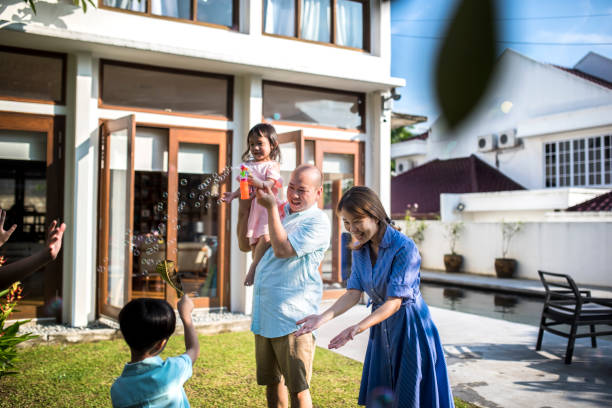 istock Chinese family playing with bubbles in the front yard 981764028