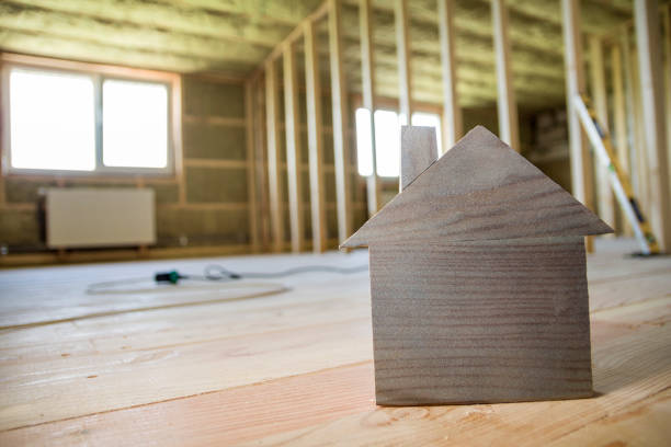 Close-up of simple small brown model house on blurred building tools background. Construction, building and investments in real estate, property and ownership of dream home concept.
