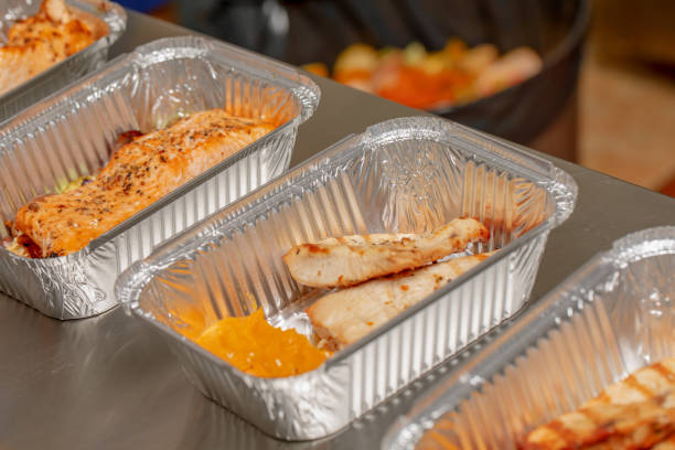 Multiple meals ready to eat packaged in aluminum disposable food containers, take away healthy food restaurant concept. Healthy cooking, protein rich diet background, turkey fillets and salmon steaks. múltiples comidas listas para consumir envasados en recipientes de aluminio desechables de alimentos, llevar concepto de restaurante de comida sana. healthy cooking, antecedentes de dieta rica en proteína, filetes de salmón y los filetes de pavo.
