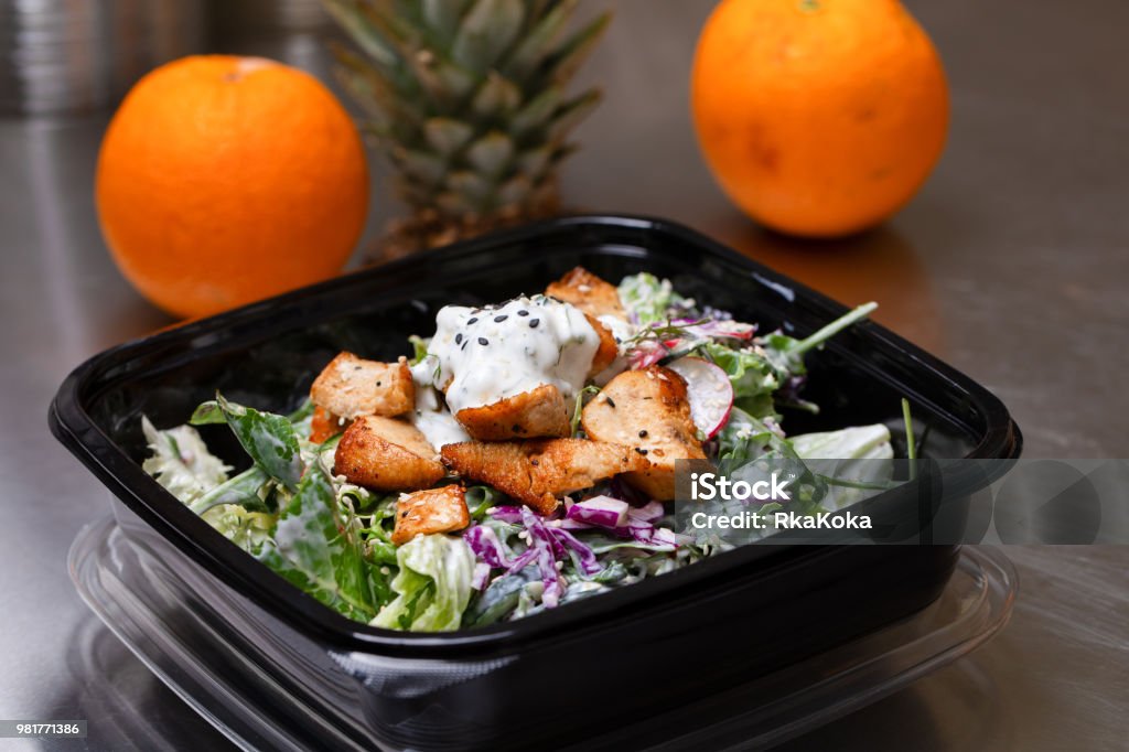Fresh salad meal packed in a plastic container ready to eat - Healthy takeaway food and eating concept Fresh salad meal packed in a plastic container ready to eat - Healthy takeaway food and eating concept. Shot in a real healthy fast food kitchen, ready for delivery. Plastic Container Stock Photo