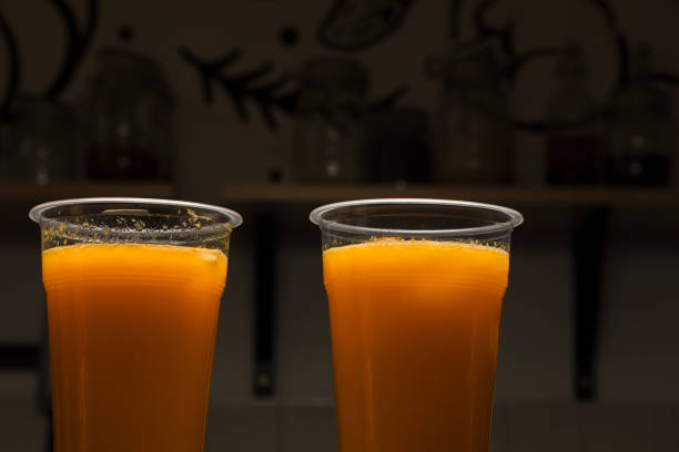 Orange juice in two plastic drinking glasses, healthy drink background with copy space. Packaged fresh drink ready for take away or food delivery, vitamin c refreshment - Detox and dieting on the go.