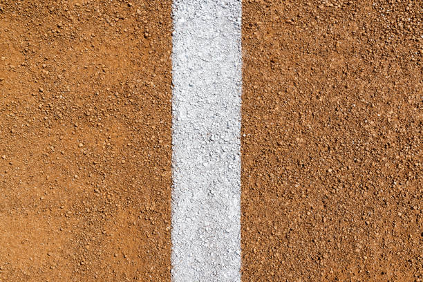 Overhead view of white Foul Line on dirt of baseball diamond An overhead view of a painted white Foul Line on dirt of a baseball field infield diamond. Sometimes this can be referred to as a Fair Line as it is in Fair Territory and the area from the edge of the line is Foul Territory. foul stock pictures, royalty-free photos & images
