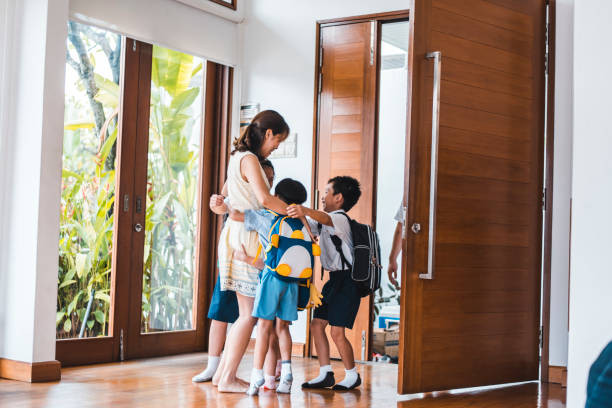 istock Children coming home from school and hugging their mother 981775154