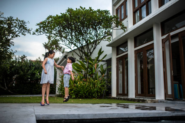 istock Chinese brother and sister jumping in the front yard 981775196
