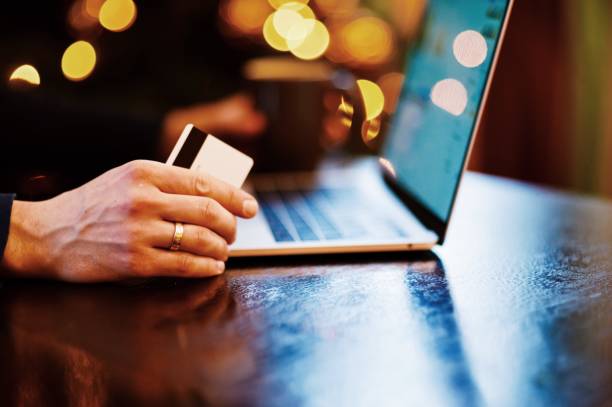 istock Cropped Hands Of Man Holding Credit Card While Using Laptop At Table 981776330