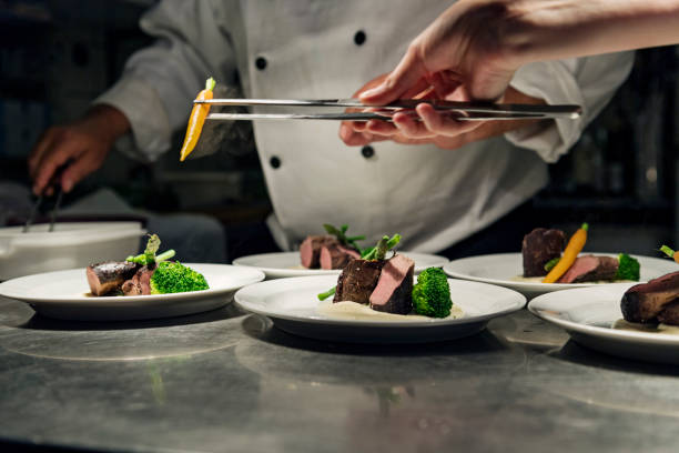 chef professionnel au travail dans une cuisine bien remplie se prépare pour le service - haute gastronomie photos et images de collection