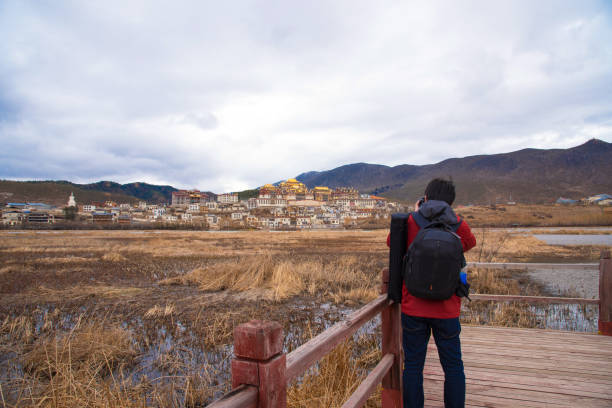 uomo turistico che scatta una splendida vista paesaggistica del monastero di songzanlin marchio di terra del tempio d'oro nella città di shangri-la, in cina - yunnan province tibetan culture tibet asian culture foto e immagini stock