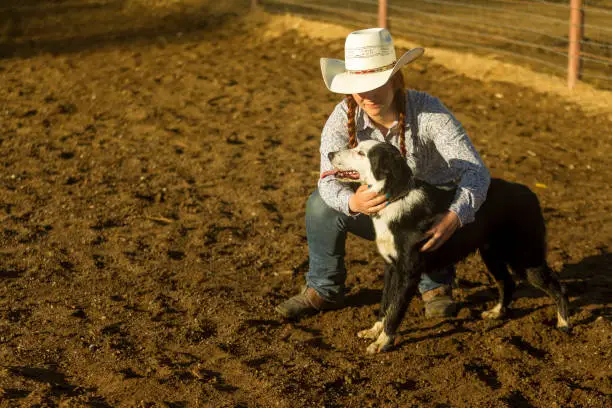 redhat cowgirl with hat petting dog at ranch in Salt Lake City SLC Utah USA