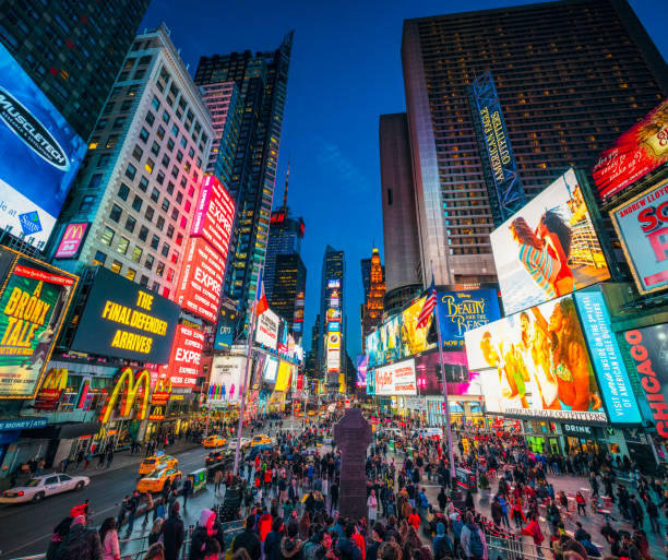 Times Square in New York City at dusk Times Square covered with illuminated billboards during the 'blue hour' period at dusk, with tourists on the streets. advertisement stock pictures, royalty-free photos & images