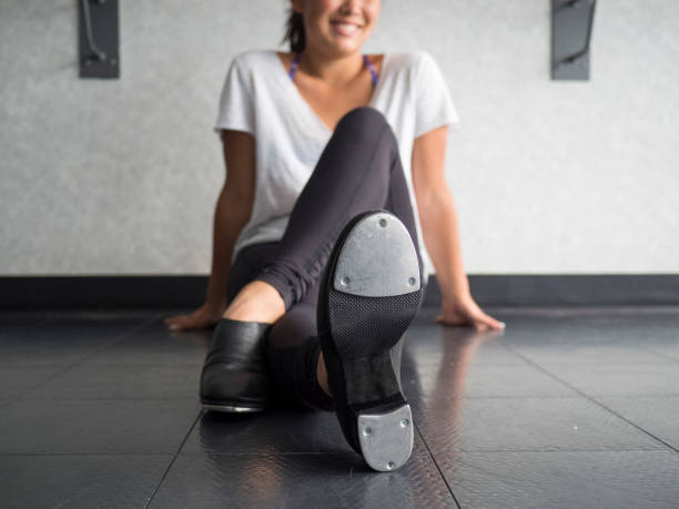 Smiling teenage tap dancer sitting cross legged in dance class relaxing Smiling teenage tap dancer sitting cross legged in dance class relaxing tapping stock pictures, royalty-free photos & images