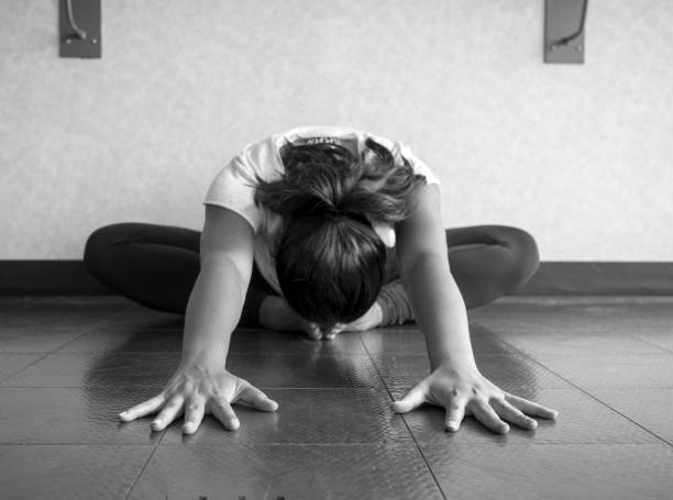 istock Black and white version of Yoga dancer Hip stretch in butterfly position reaching forward head to feet 981817146