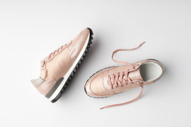 Pastel pink female sneakers on white background.