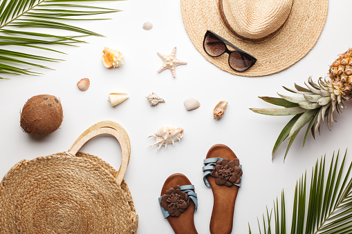 Summer composition. Fruits, hat, tropical palm leaves, seashells on white background. Summer concept. Flat lay, top view, copy space.