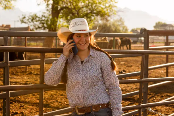 redhat cowgirl with hat smiling and talking phone at ranch in Salt Lake City SLC Utah USA