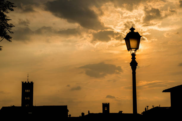 Lucca golden sunset skyline with ancient medieval towers and old street lamp