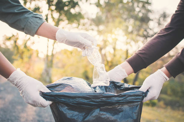 istock Cropped Hand Wearing Protective Glove While Putting Plastic Bottle In Bag 981850736