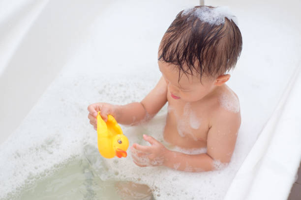 mignon petit asiatique 2 ans bambin bébé garçon enfant s’amuser assis dans la baignoire jeu caoutchouc canard jouet - male animal duck water cleaning photos et images de collection