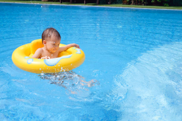 cute little asian 2 years old toddler boy child having fun playing with inflatable swim ring in outdoor swimming pool on hot summer day - swimming child swimwear little boys imagens e fotografias de stock