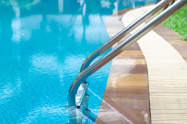 Photo of Grab bars ladder in the blue swimming pool