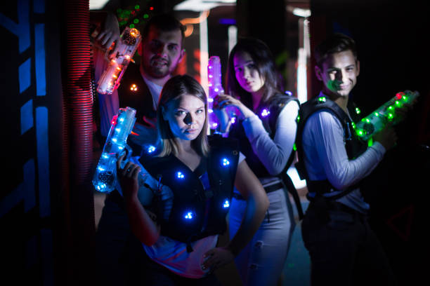 Group portrait of young people with laser guns having fun on dark lasertag arena