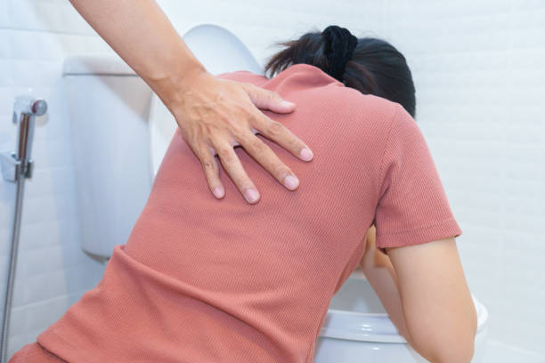 Closeup of a sick woman open toilet seat at bathroom and a friend is helping her. stock photo