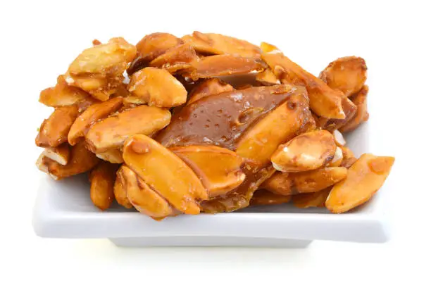 Photo of sweetened pili nuts popular delicacy in bicol, philippines in white plate on background