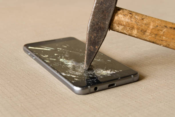 istock A hammer smashing a mobile phone on a grey background 981879724