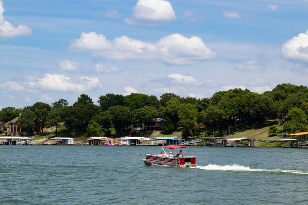 barca pontone che si diritta oltre case e banchine sulla riva in una giornata di sole al lago - motoring foto e immagini stock