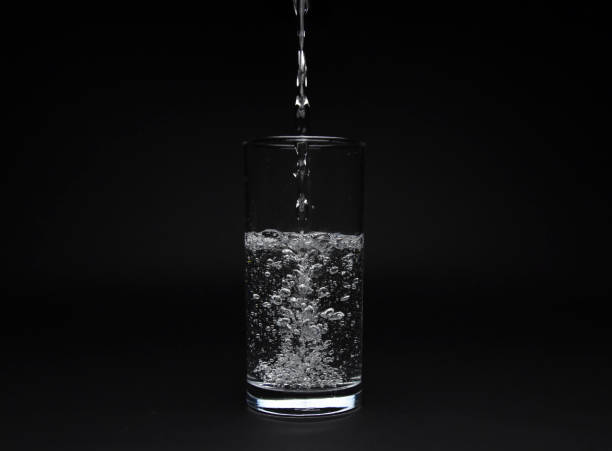 istock Half full glass of water isolated on black background 981925744