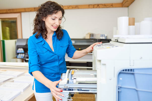 istock Adult woman checking printer in office 981930528