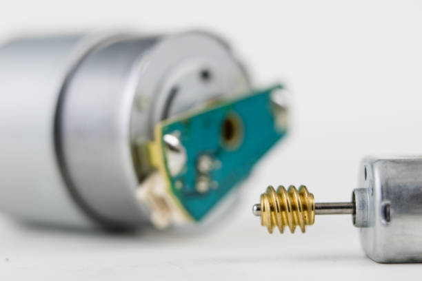 Small electric motor on a white workshop table. Electric drive used in small electrical devices. Light background.