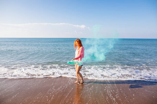 istock Woman having fun with smoke bomb on the beach 981945478