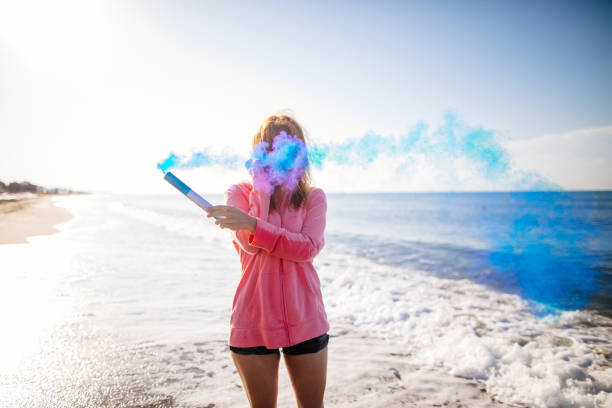 Woman having fun with smoke bomb on the beach
