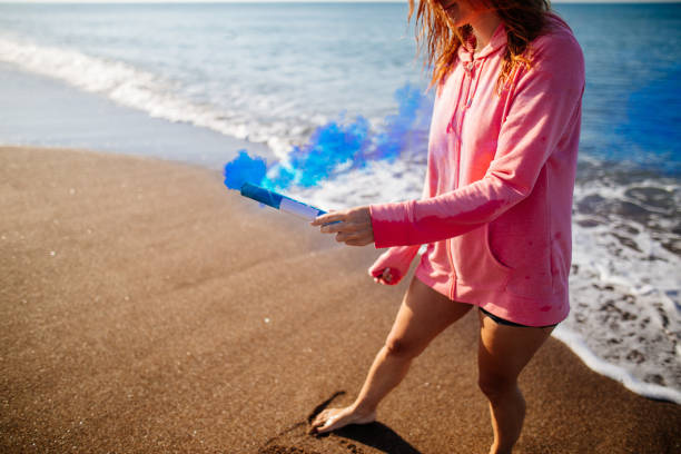 istock Woman having fun with smoke bomb on the beach 981961750