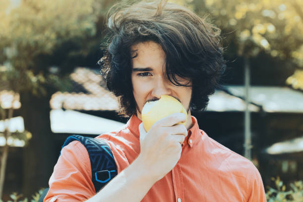 istock Handsome young man eating an apple 981998518