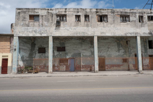 istock Run down concrete building with small apartment on the first floor. Small windows open to let in cool breeze. Old building next to the road in Havana, Cuba. 982001036