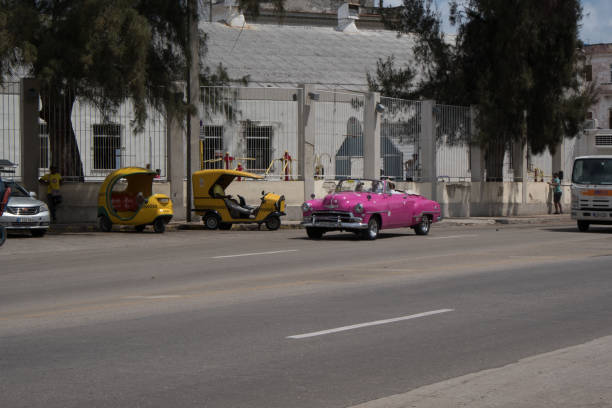 rose lecteurs de voiture américaine classique chevrolet des années 1950 dans la rue en passant deux taxis garés coco à la havane, cuba. - cuba car chevrolet havana photos et images de collection